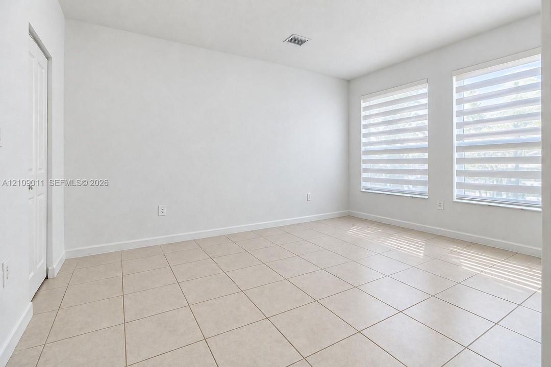 Neutral-toned tile flooring, dual windows with integrated blinds, and a multi-panel door