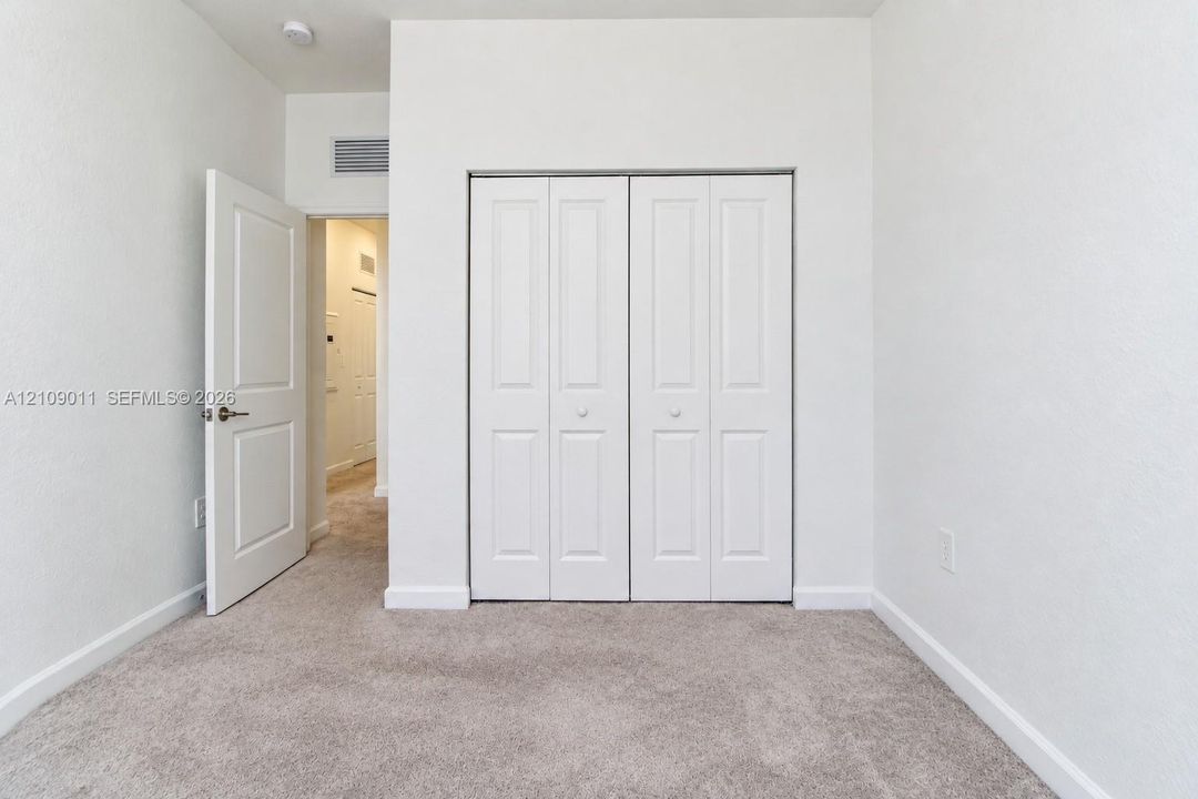 Neutral-toned carpeted flooring, white interior walls, and four-panel bi-fold closet doors