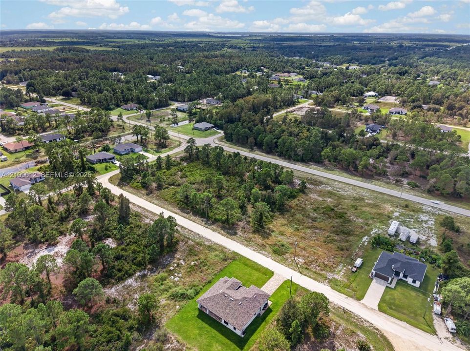 Aerial perspective of a multi-lot site featuring expansive green space, mature tree lines, and paved access roads