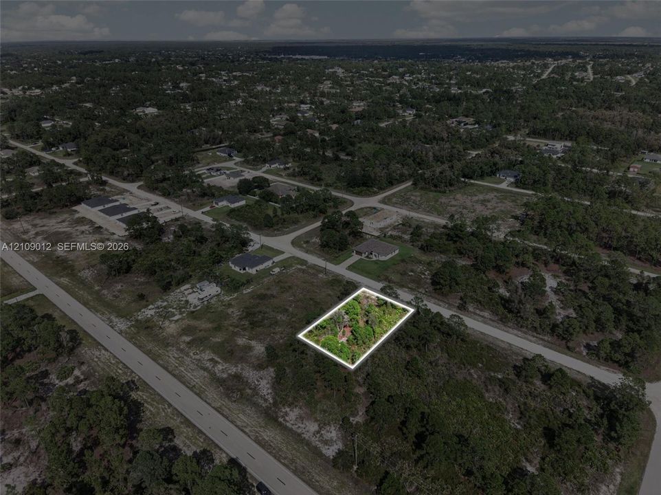 Corner lot situated in a partially developed area featuring native vegetation and direct paved road frontage