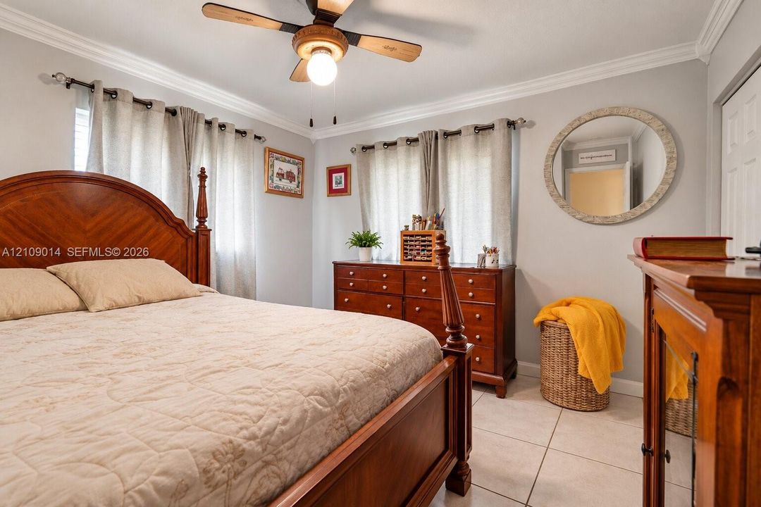 Neutral-tone room featuring crown molding, large-format tile flooring, and a ceiling fan with integrated lighting