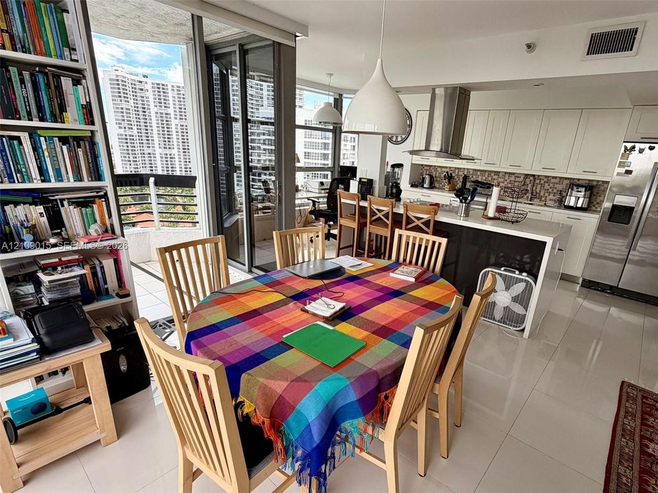 Open-concept kitchen featuring crisp white cabinetry, a large kitchen island with a stone-finish countertop, stainless steel appliances, and tile flooring
