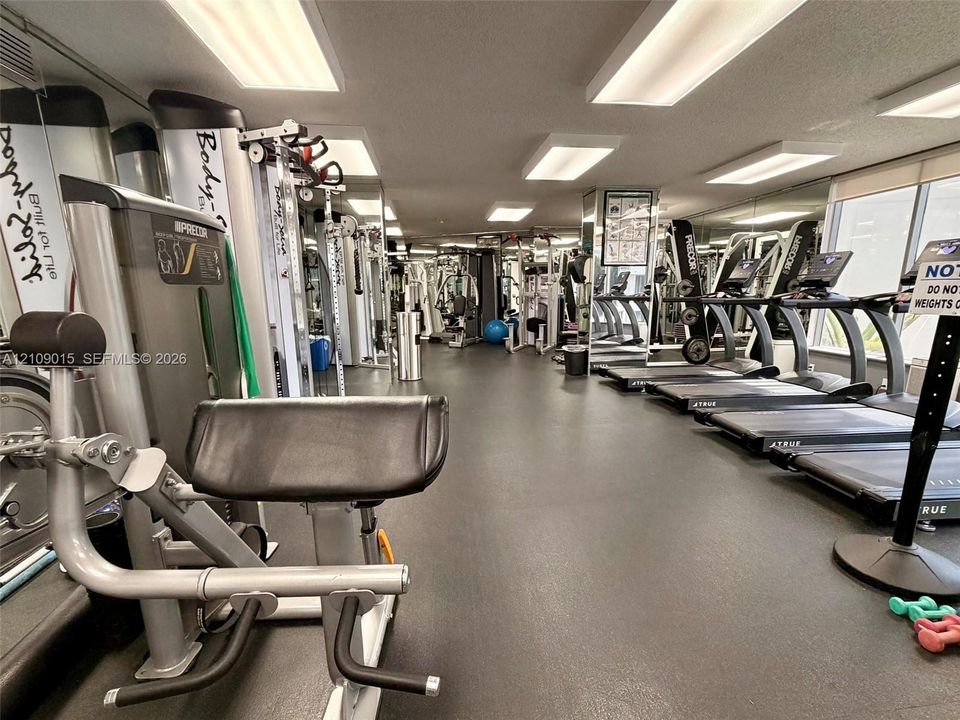 Fitness center featuring rubber flooring, recessed ceiling lighting, and wall-to-wall mirrored surfaces
