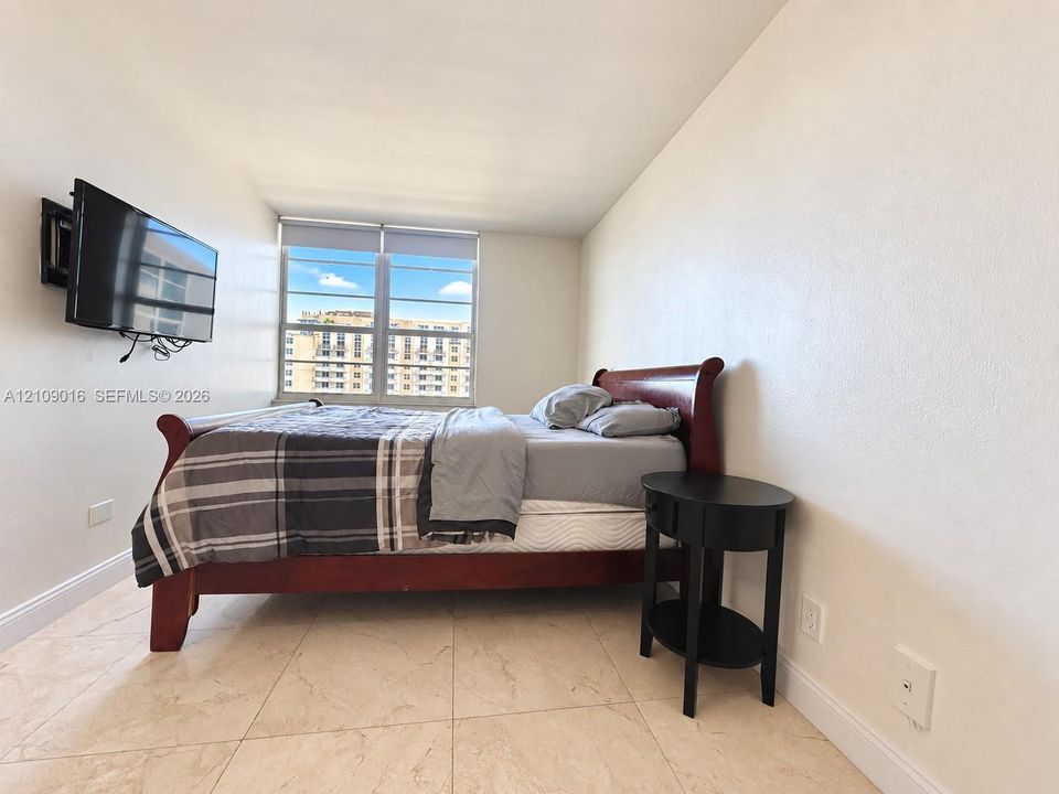 Large-format tile flooring and wide window with neutral-toned roller shade
