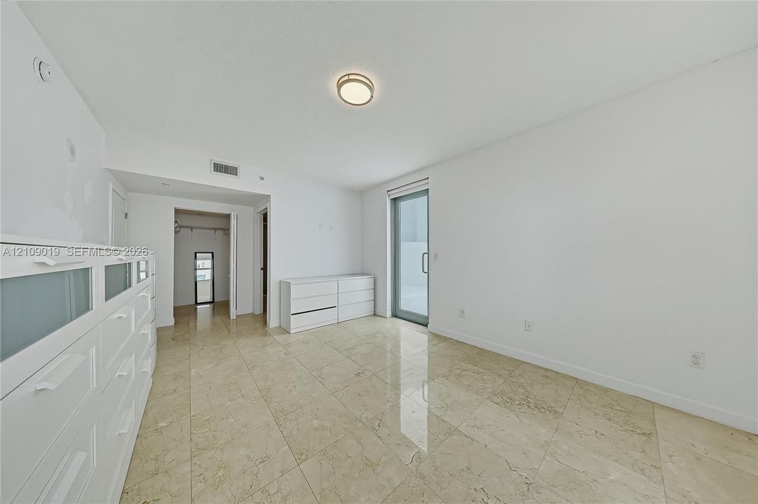 Polished stone flooring, recessed ceiling lighting, and a glass-paneled door
