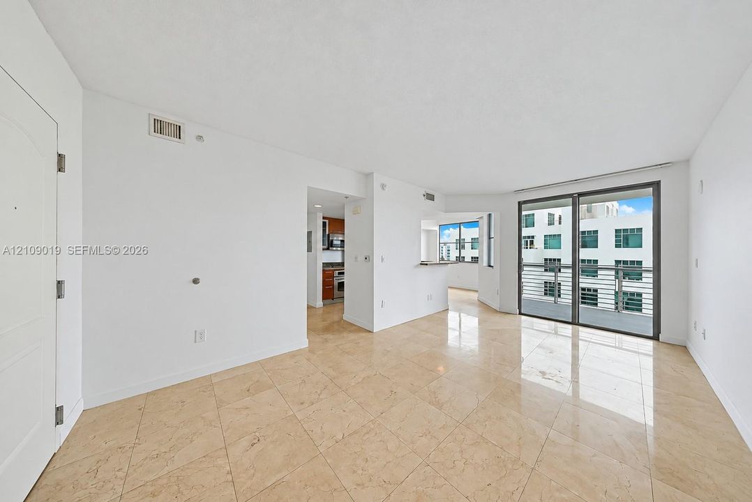Open floor plan featuring tile flooring, built-in breakfast bar, and floor-to-ceiling sliding glass doors opening to a balcony