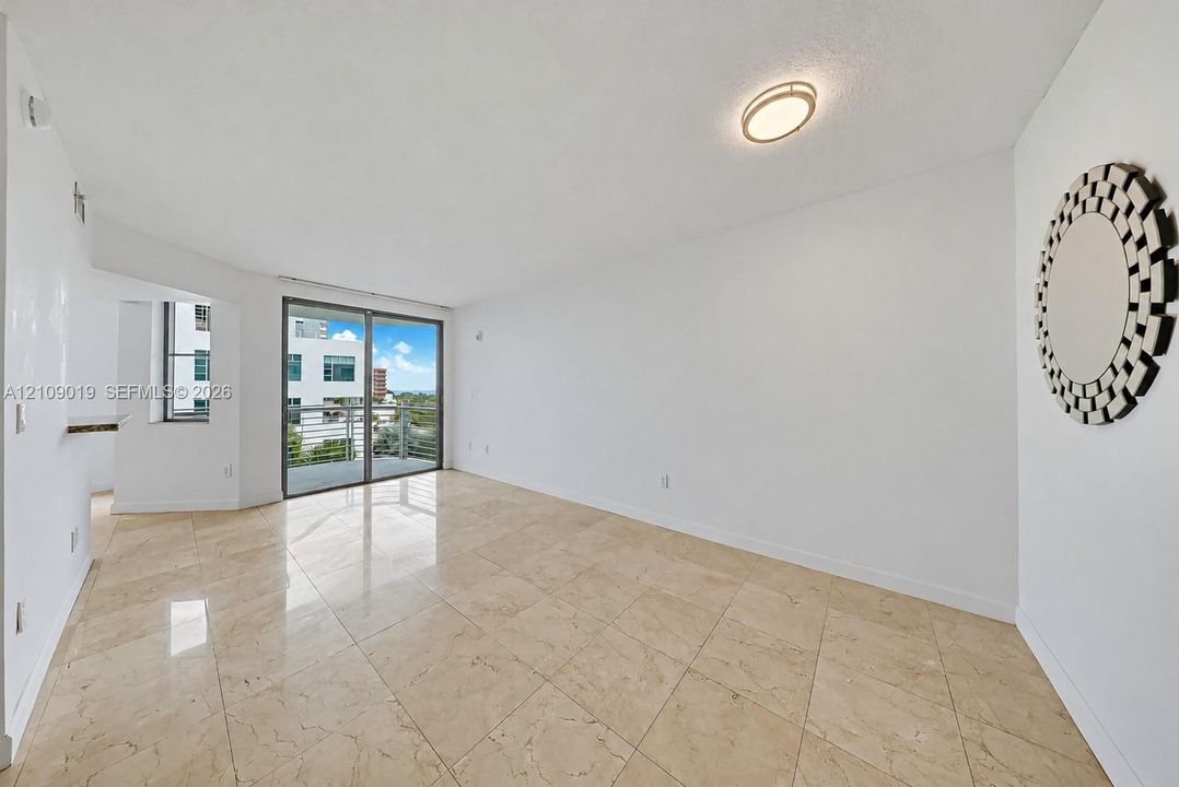 Open-concept interior featuring large-format tile flooring, recessed ceiling lighting, and sliding glass doors with access to an exterior balcony