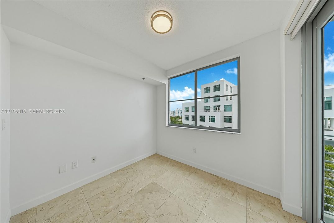 Room interior featuring large-format stone flooring, expansive aluminum-framed windows, and a flush-mount circular ceiling fixture