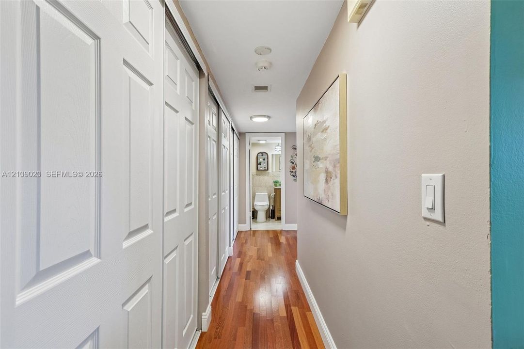 Hallway featuring wood-finish flooring, dual sliding-panel closet doors, and recessed lighting