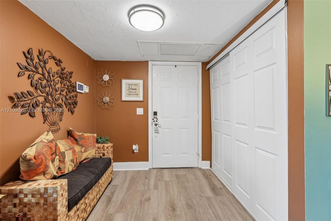 Entryway featuring light-toned wood-finish flooring, white six-panel door, and a sliding white closet door with a six-panel design