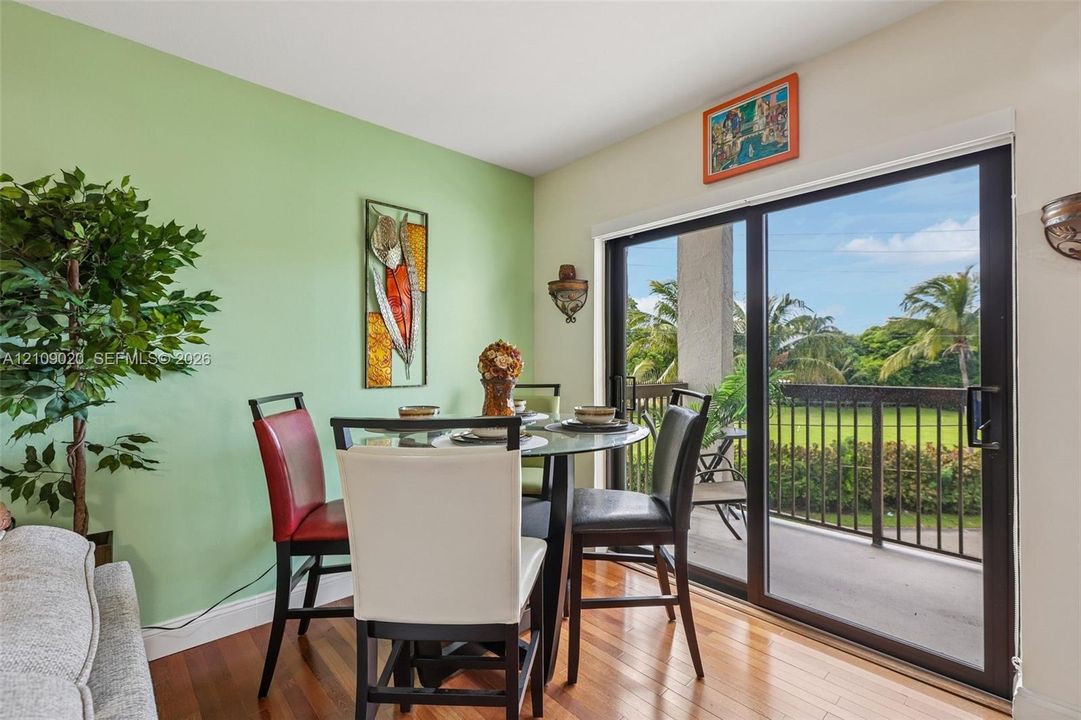 Wood-finish flooring, sliding glass door, metal balcony railing, and wall-mounted light fixtures