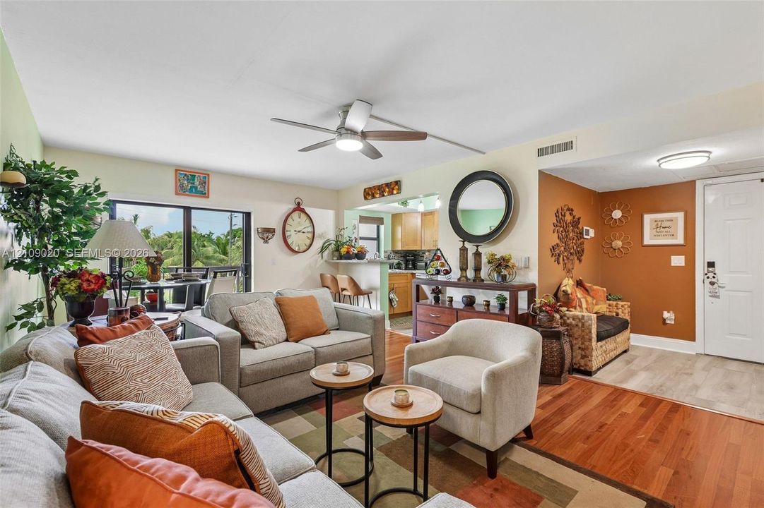 Open-concept living area featuring wood-finish flooring, a ceiling-mounted light fixture with fan, and a neutral color palette
