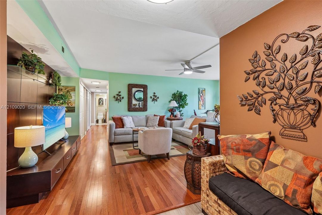 Wood-finish flooring, built-in dark wood media cabinetry, and a ceiling fan