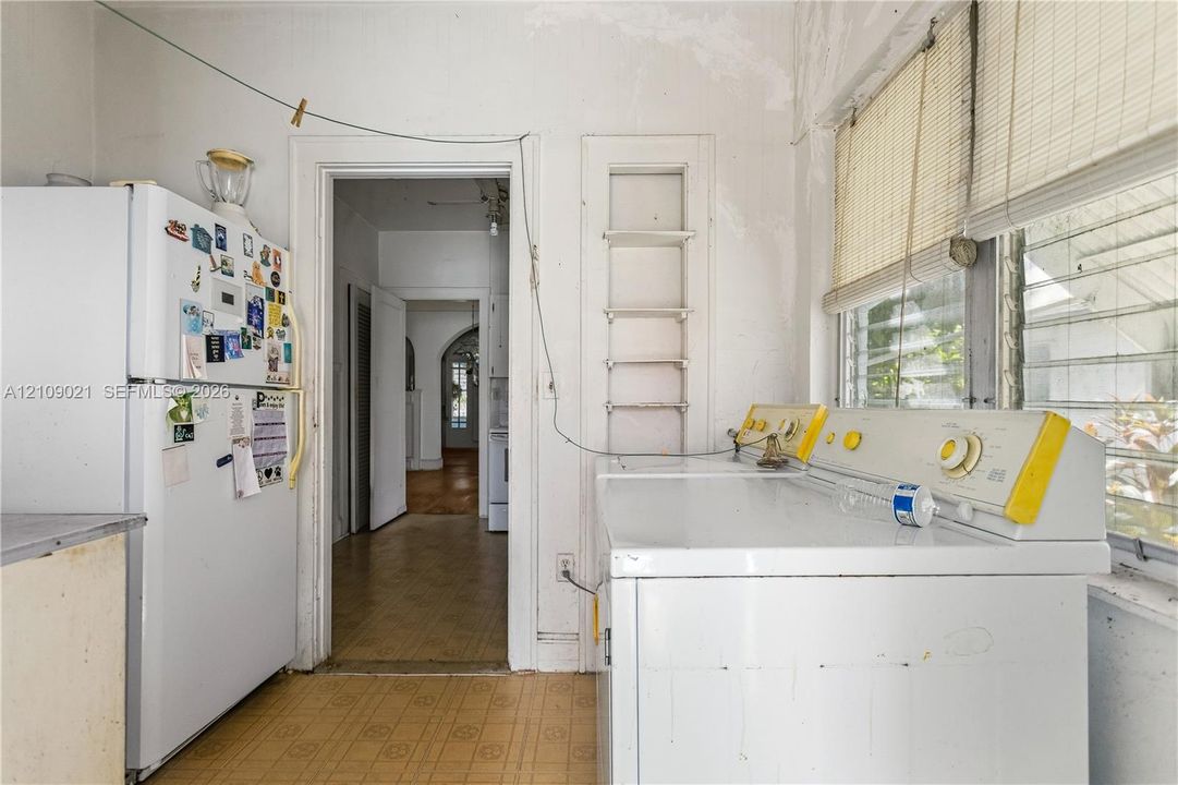 Laundry area featuring built-in recessed wall shelving, louvered windows, and hard-surface flooring
