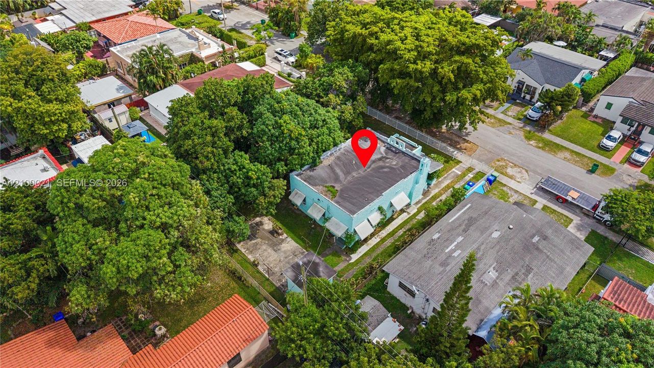 Aerial view featuring a low-rise residential building with a flat roofline, integrated window awnings, and a paved surface parking area situated within a developed neighborhood