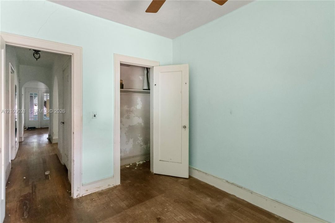 Room featuring wood-finish flooring, a built-in closet with shelving, and arched entryways