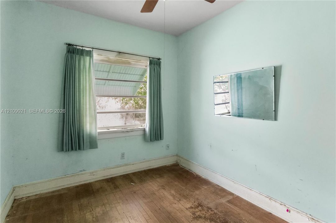 Hardwood flooring, wall-mounted mirror, and louvered window with exterior metal awning