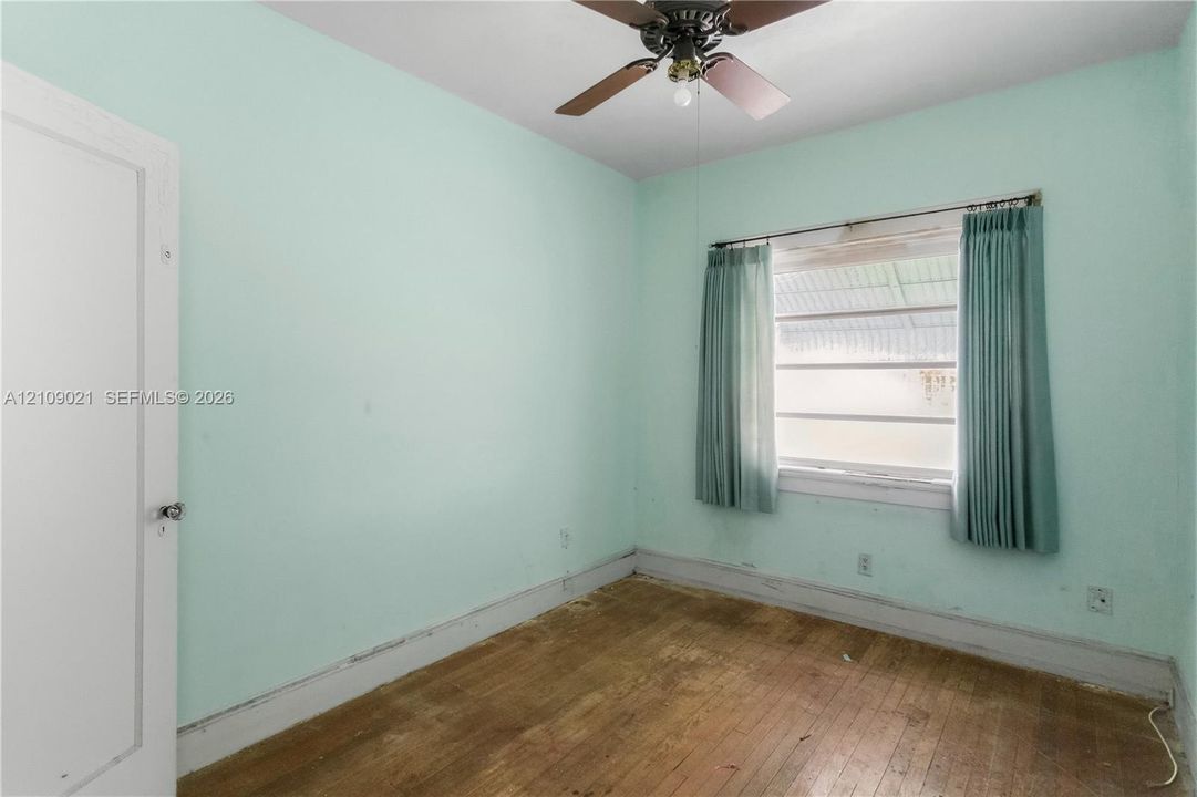 Room featuring wood-finish flooring, a ceiling fan with integrated lighting, and a multi-pane horizontal window