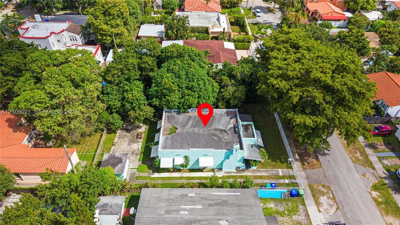 Aerial view of a detached structure featuring a low-slope roof, exterior wall-mounted awnings, and an outdoor fireplace chimney