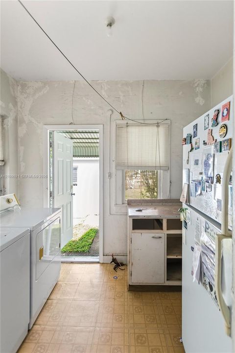 Utility room featuring resilient square-tile flooring, an exterior door, a single-hung window, and a built-in base cabinet with a countertop