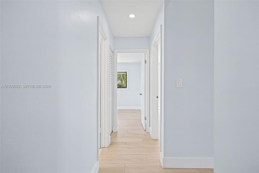 Hallway featuring light-toned wood-finish flooring, recessed lighting, and white door casings
