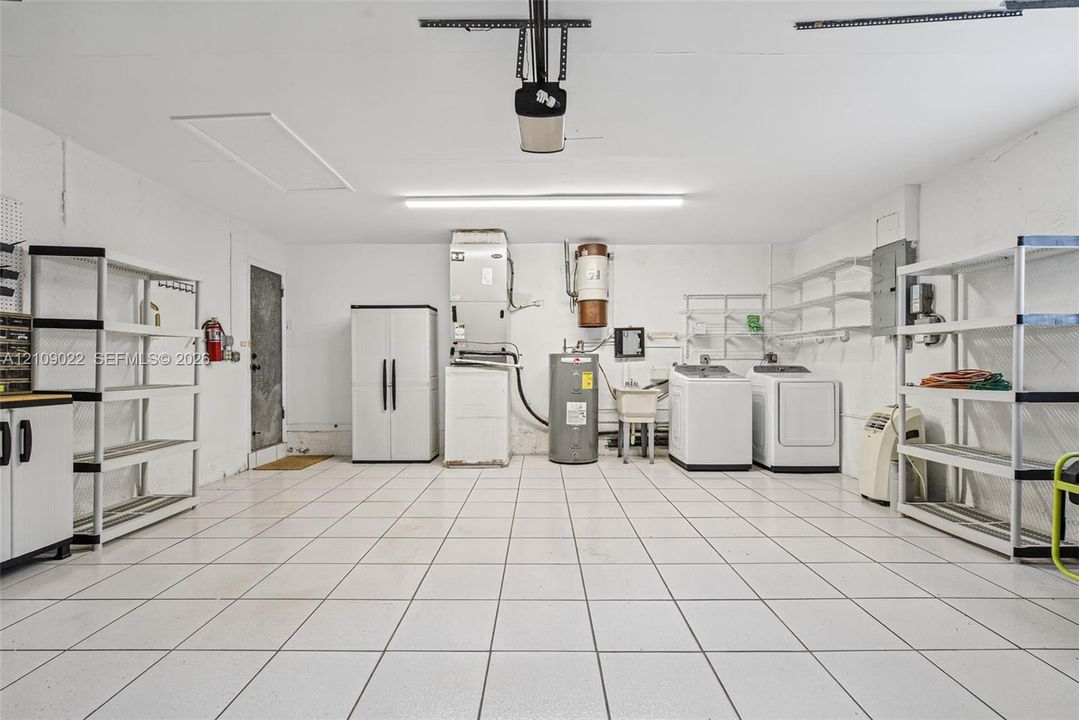 Finished garage space featuring ceramic tile flooring, a dedicated utility sink, and an integrated overhead garage door opener