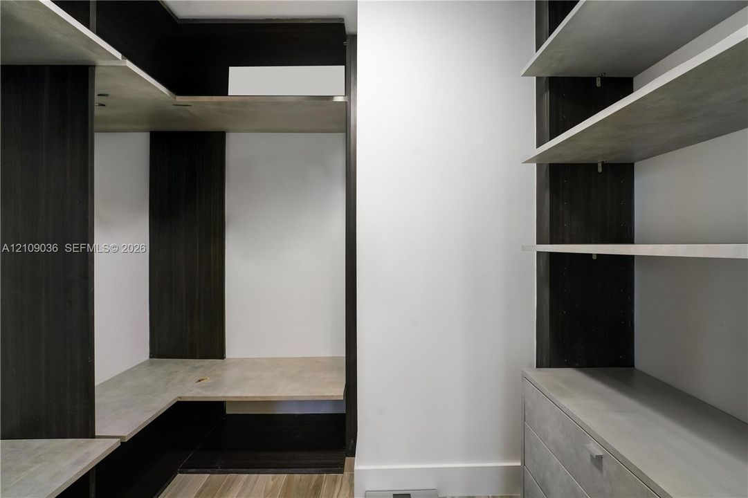 Custom built-in storage system featuring dark wood-tone cabinetry, multiple open shelving tiers, integrated drawer units, and light-toned horizontal surfaces