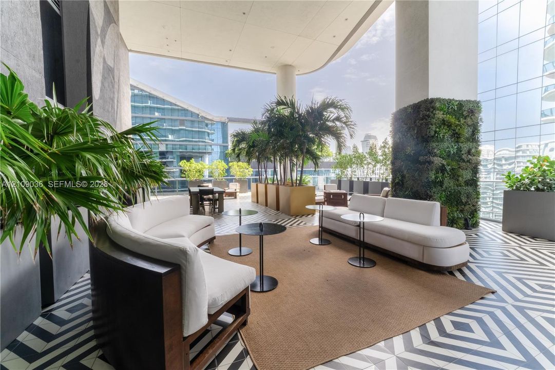 Covered terrace featuring geometric patterned floor tiling, a living wall installation, and glass paneled railings