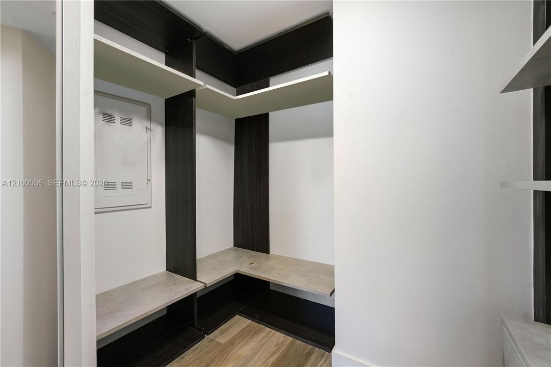Built-in storage system featuring dark-finish vertical shelving, wood-finish flooring, and stone-finish horizontal shelving surfaces
