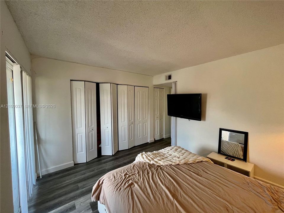 Interior space featuring wood-finish flooring, white bi-fold closet doors, and vertical window blinds