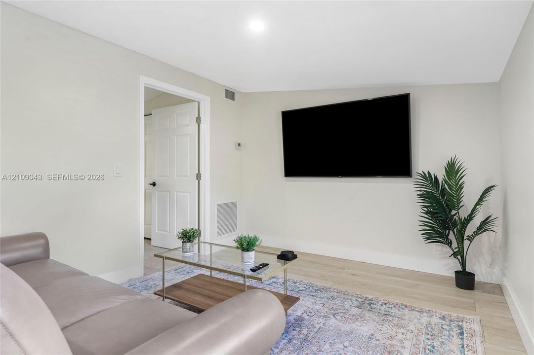 Neutral interior featuring wood-finish flooring, recessed lighting, and a six-panel interior door