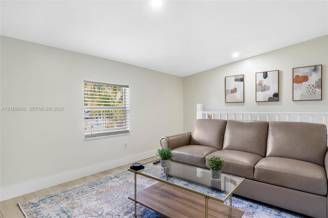 Neutral interior featuring wood-finish flooring, recessed lighting, and a white wooden stair railing