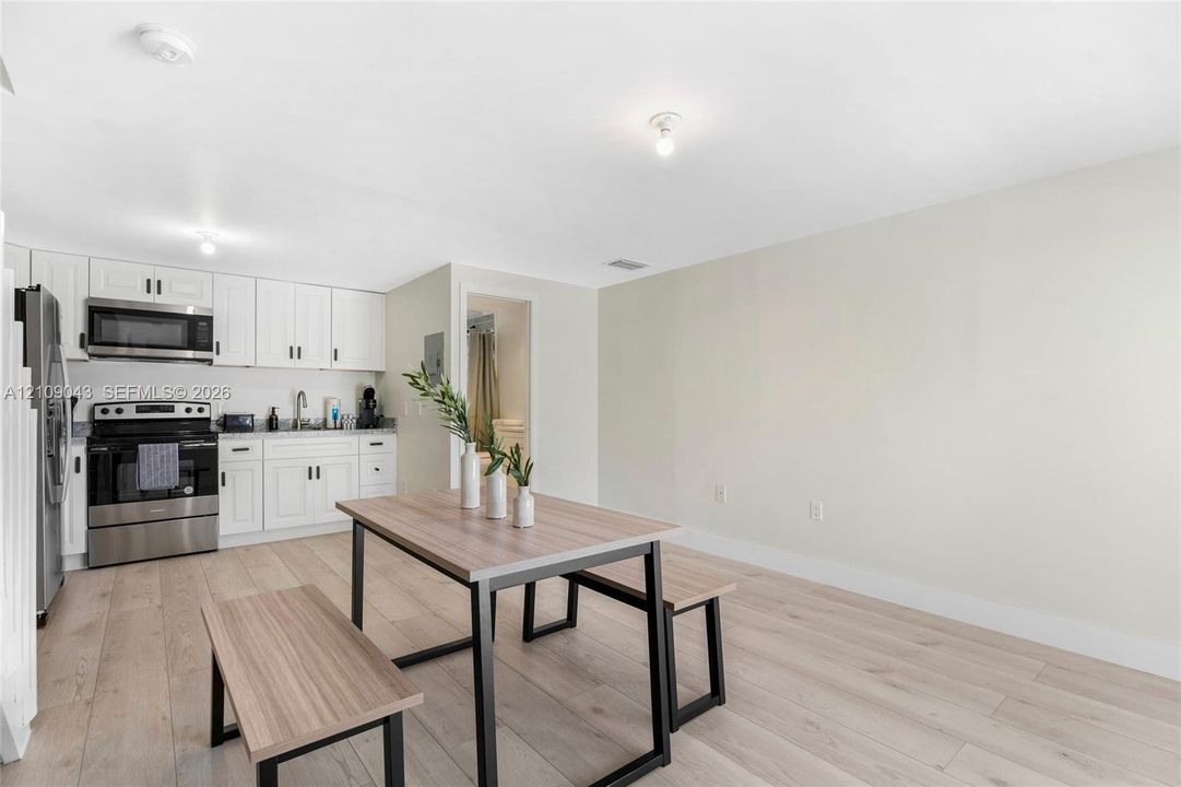 Kitchen featuring white shaker-style cabinetry, stainless steel appliances, and wood-finish flooring