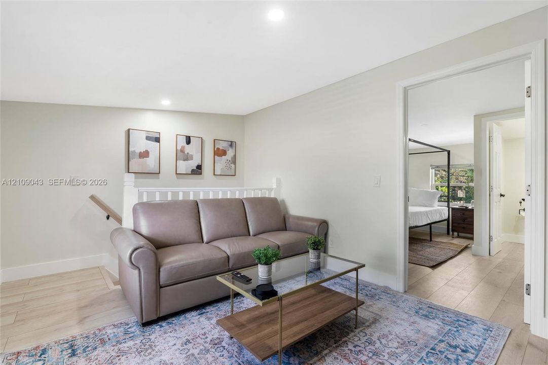 Neutral wall paint, wood-finish flooring, and white spindle railing with a wooden handrail
