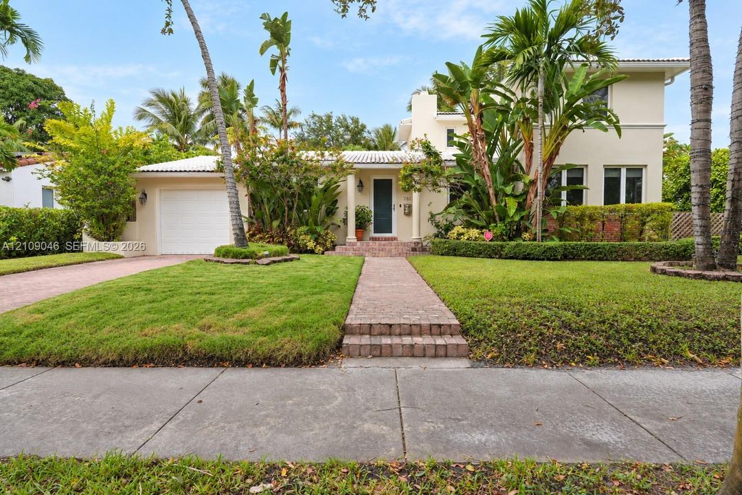 Two-story exterior featuring light-toned stucco siding, a tiled roof, a multi-paneled garage door, and a brick-paved walkway leading to a covered entry