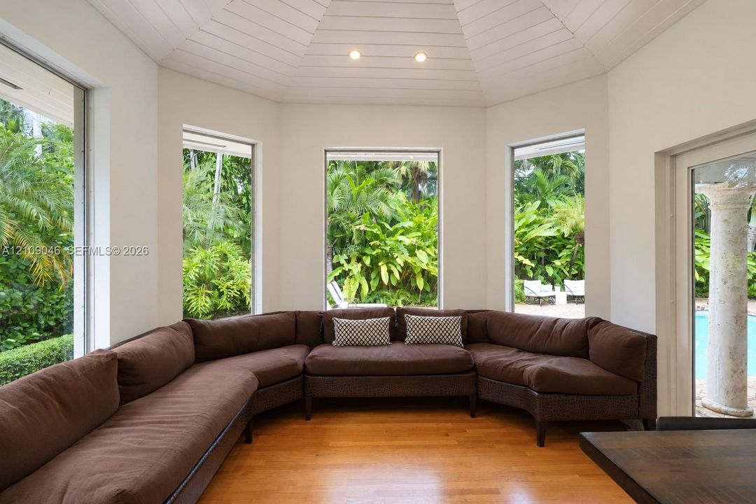 Octagonal room featuring wood flooring, plank-paneled ceiling, and multiple floor-to-ceiling windows