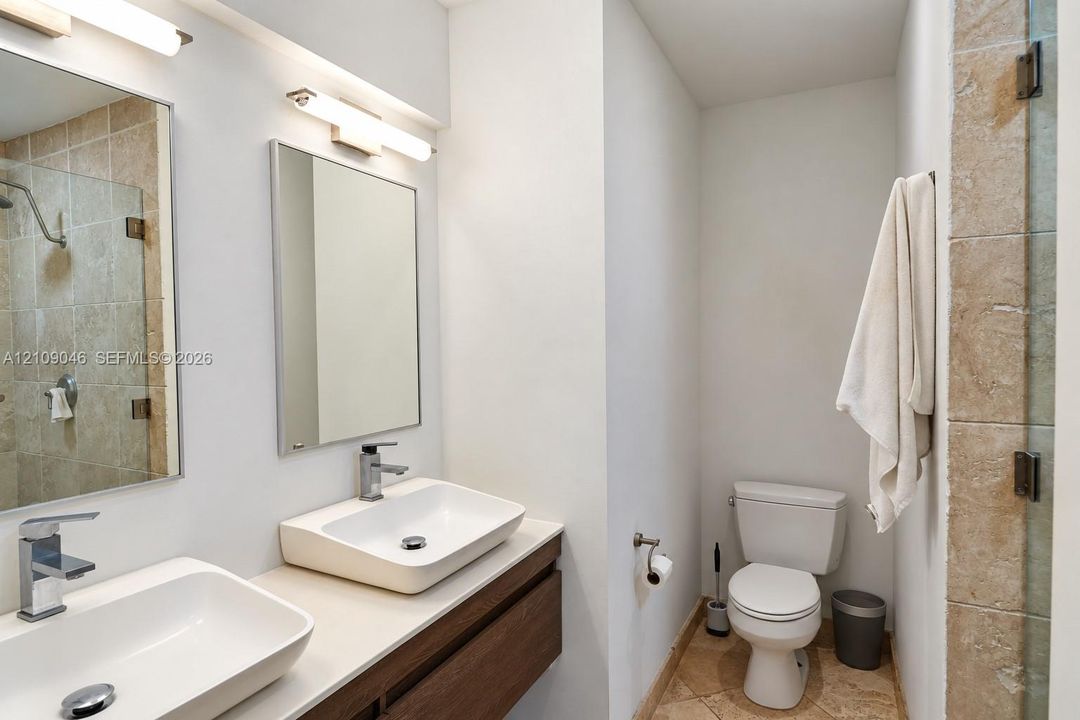 Floating dual-sink vanity with a solid surface countertop, rectangular vessel sinks, chrome fixtures, and wall-mounted light fixtures