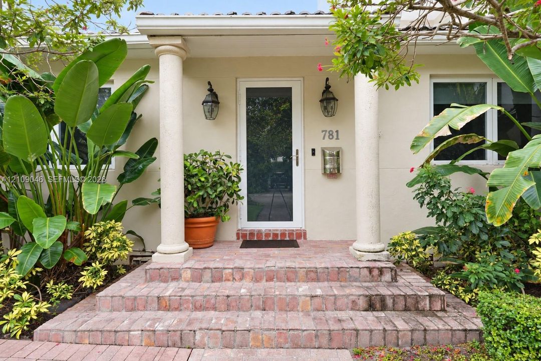 Covered entryway featuring structural columns, decorative brick steps, wall-mounted exterior lanterns, and a glass-paneled screen door