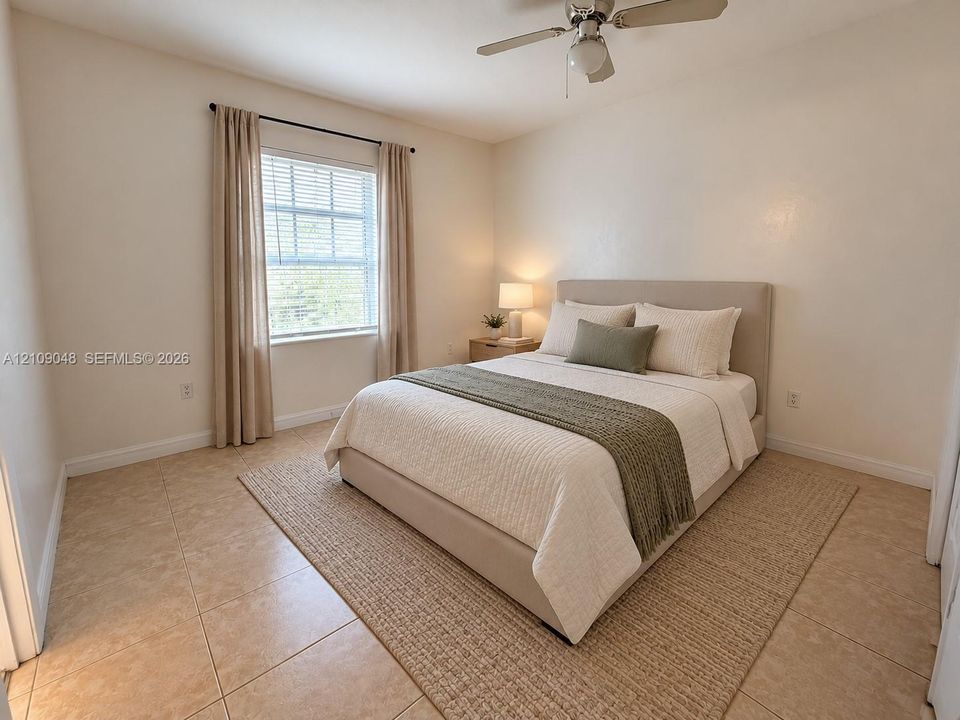 Neutral-toned room featuring large-format ceramic floor tiles, a dual-pane window, and a ceiling fan with integrated light fixture