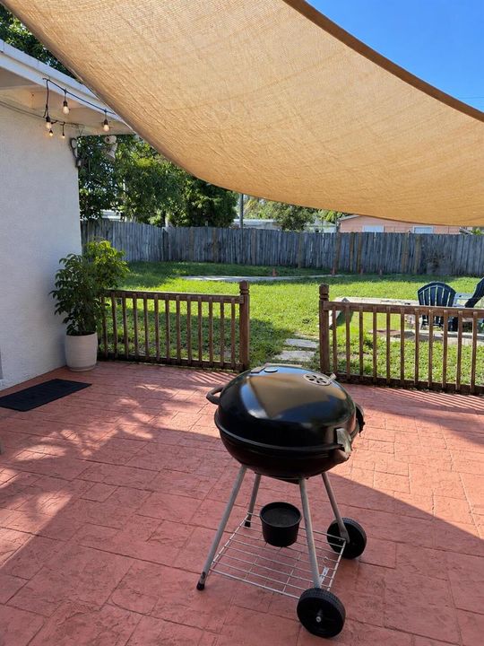 Sunny Backyard Patio with Grill and Shad