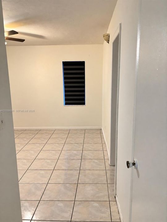 Interior space featuring neutral tile flooring, a ceiling fan, and a wall-mounted light fixture