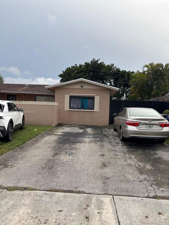 Stucco exterior featuring a gabled roofline and an expansive asphalt driveway