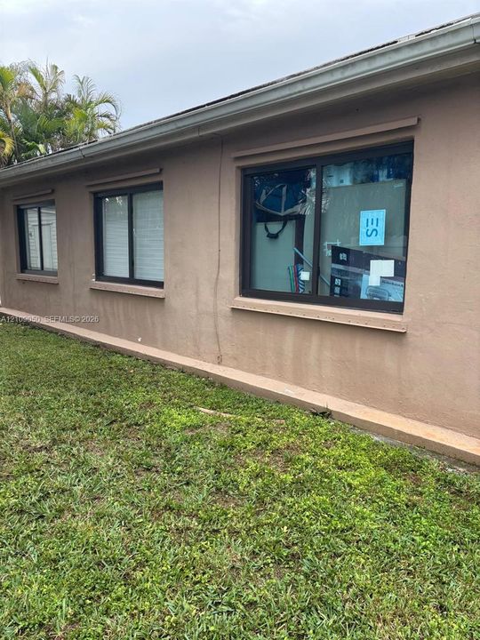 Stucco exterior featuring dual-pane windows with bronze-tone frames and a concrete foundation ledge