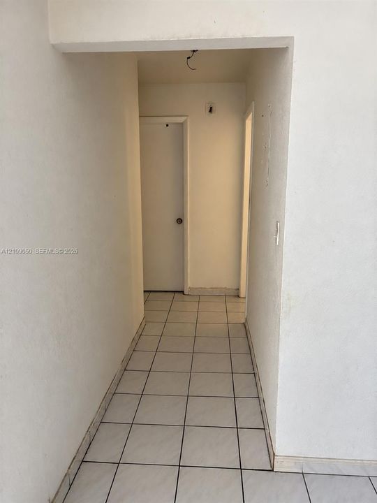 Hallway featuring white ceramic tile flooring and interior slab doors