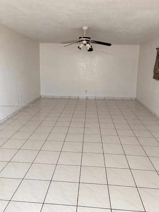 Neutral interior room featuring large-format ceramic tile flooring and a ceiling-mounted fan with integrated lighting