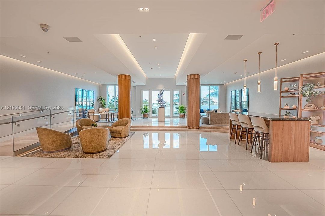 Open-concept interior featuring polished tile flooring, wood-clad structural columns, integrated cove lighting, and a built-in bar with matching cabinetry