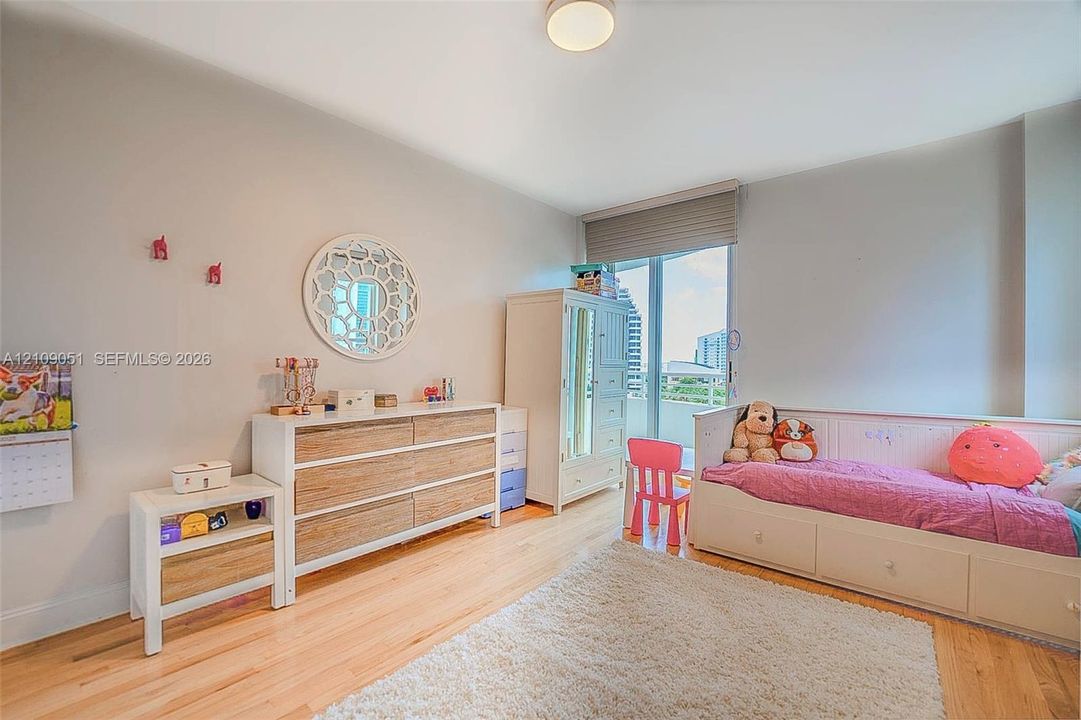 Neutral-toned walls, wood-finish flooring, flush-mount ceiling lighting, and floor-to-ceiling glass panel door with integrated window shade