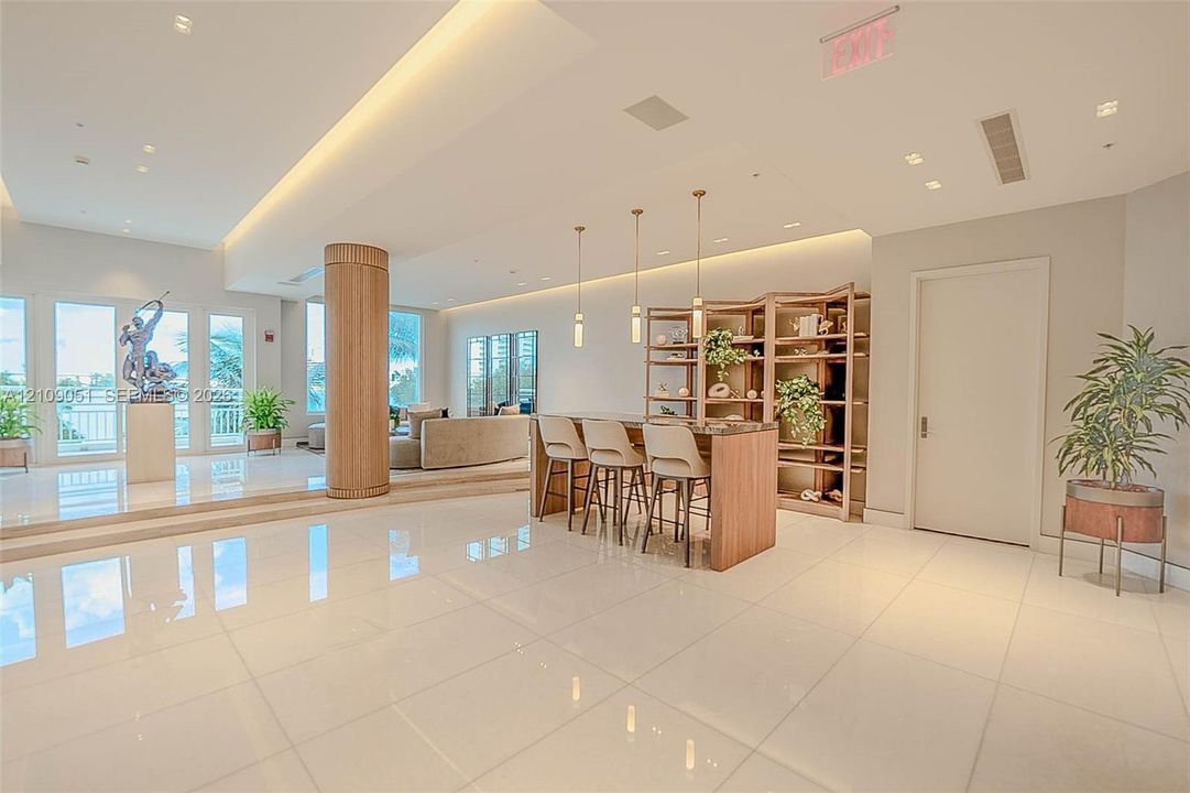 Spacious common area featuring polished tile flooring, tray ceilings with recessed lighting, a wood-wrapped structural column, and custom built-in shelving