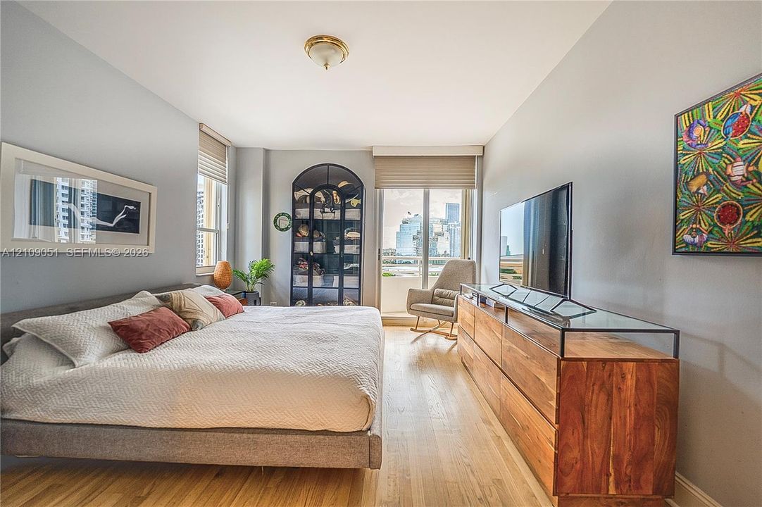 Wood-finish flooring, built-in arched display cabinetry with glass shelving, large-format windows with custom shades, and a glass-paneled entry door