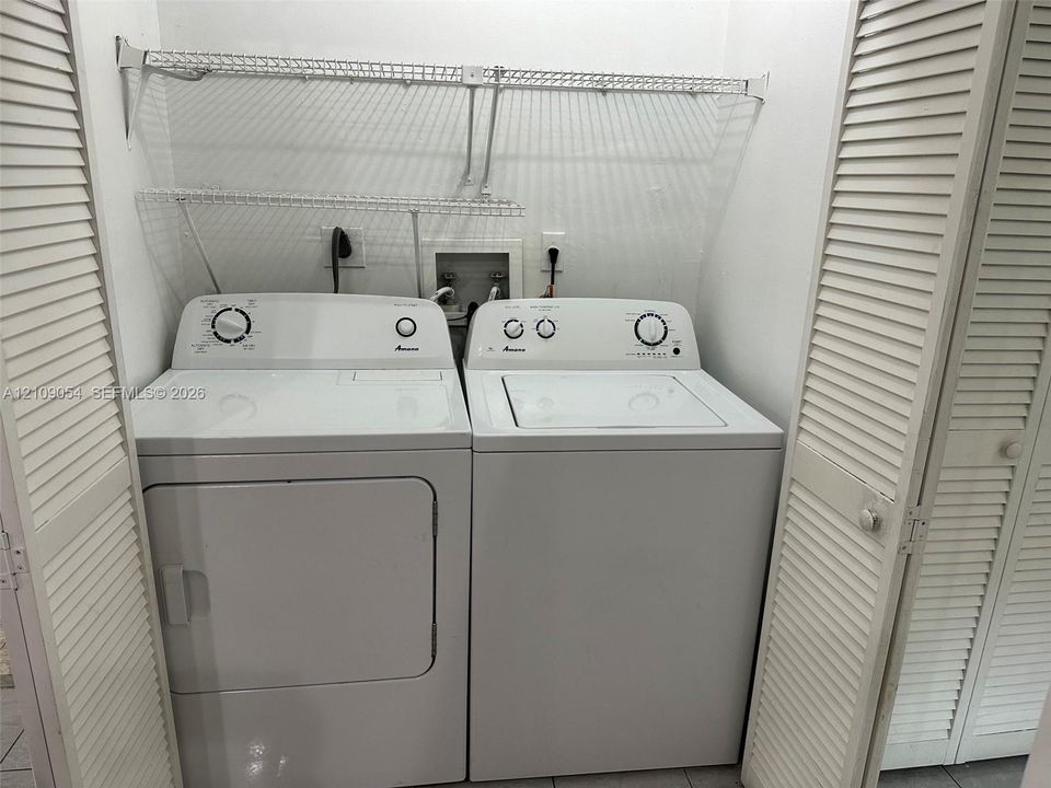 Laundry space featuring louvered bi-fold closet doors, wall-mounted wire shelving, and dedicated utility hookups